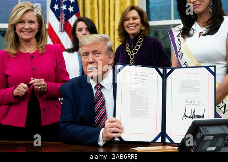 US-Präsident Donald J. Trumpf (C) bis "das Frauenwahlrecht Centennial Gedenkmünze Act', nach Unterzeichnung während einer Zeremonie, neben United States Senator Marsha Blackburn (Republikaner von Tennessee) (L), im Oval Office des Weißen Hauses in Washington, DC, USA, 25. November 2019. Trumpf 'H.R. 2423, das Frauenwahlrecht Centennial Gedenkmünze Act" - eine Rechnung, die Leitung der US Treasury, Minze und Ausgabe von bis zu 400.000 one-dollar Silber Münzen ehrt Frauen, die eine Rolle bei der Unterstützung für den Änderungsantrag 19. Wir sammeln: Michael Reynolds/Pool über CNP | u gespielt Stockfoto