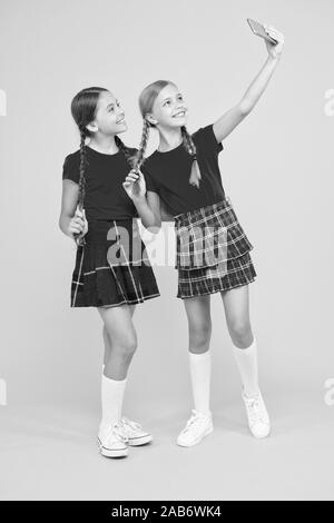 Familie Abbinden. Schwesternschaft und Freundschaft. Glücklich wissen Tag. Kindheit Glück. Bildung Konzept. zurück zu Schule. sozialen Netzwerk. Mädchen in Uniform. kleine Mädchen selfie am Telefon machen. Spaß haben. Stockfoto