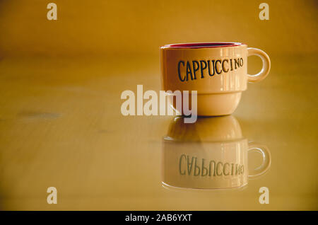 Eine Tasse leer Cappuccino auf einem Holztisch mit Glas Stockfoto