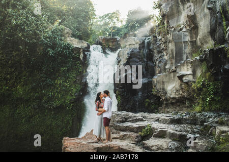 Junges Paar in Liebe Küssen mit fantastischen Blick auf Tegenungan Kaskade Wasserfall. Glücklich zusammen, die Flitterwochen auf Bali. Reisen Lifestyle. Stockfoto