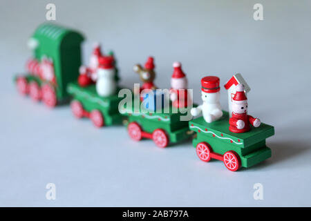 Grüne festliche Holz- Zug entfernt reiten auf weißem Hintergrund mit kopieren. Selektiver Fokus auf Schneemann. Weihnachten und neues Jahr Spielzeug mit Figuren von Mou Stockfoto