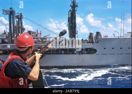 Philippinischen MEER (Aug. 24, 2012) ist ein Gunner Mate 2. Klasse der Arleigh-Burke-Klasse geführte Anti-raketen-Zerstörer USS McCampbell (DDG85), feuert einen Schuß an die militärischen Sealift Command flotte Auffüllung öler USNS Tippecanoe (T-AO 199) während einer Auffüllung auf See. Stockfoto