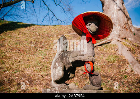 Kitsune japanische Fox steinerne Statue mit roten scarft und Hut am Schrein von Aizu Wakamatsu Tsuruga Schloss - Nahaufnahme Gesicht Details - Japan Gott guard Fox Stockfoto