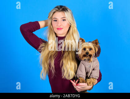 Mädchen adorable blonde Hug kleiner Hund im Wappen. Bekleidung und Accessoires. Heimtierbedarf. Abrichten Hund für kaltes Wetter. Die Hunderassen sollten Mäntel tragen. Frau tragen Yorkshire Terrier. Hunde brauchen Kleidung. Stockfoto