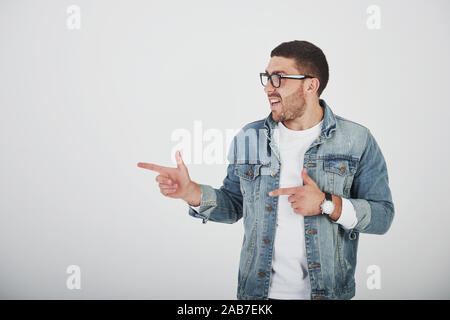 Glücklich, aufgeregt, bärtigen Mann in Brillen an Kamera mit Smile suchen und auf Kopieren Raum mit zwei Fingern isoliert auf weißem Hintergrund Stockfoto
