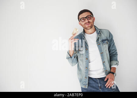 Jungen gutaussehenden männlichen Business Executive in lässige Kleidung, die eine Kreditkarte in den Taschen auf einem weißen Hintergrund. Das Konzept des Handels am Stockfoto