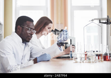 Wissenschaftler arbeiten eng mit dem Mikroskop im Labor durch Experimente und Analysen. Stockfoto