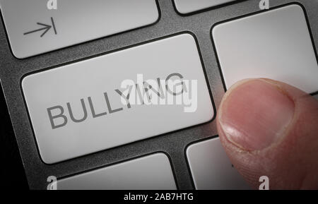 Ein Mann durch Drücken einer Taste auf einer Computertastatur mit dem Wort Mobbing, online Mobbing Konzept Bild Stockfoto