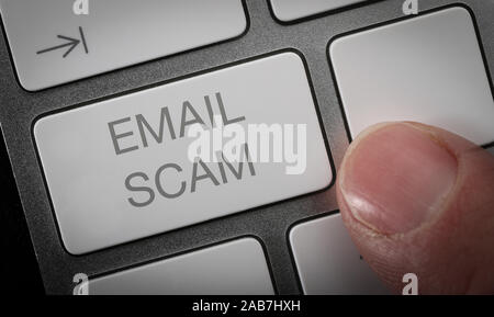 Ein Mann durch Drücken einer Taste auf einer Computertastatur mit den Worten e-Mail scam. Stockfoto