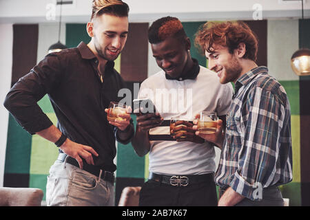 Vielversprechende junge multi-ethnische Menschen feiern und trinken Whiskey Toast, Watch gadget Stockfoto