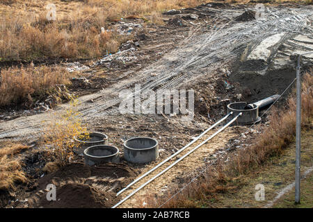 Der Prozess der Festlegung von Engineering- und Heizungssysteme. Rohre in einem Graben von Boden sind. Die Verlegung für Abwasser Stockfoto