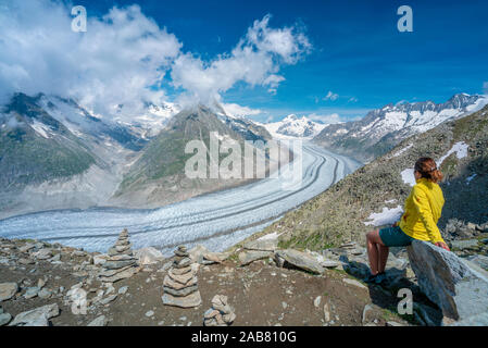 Seitenansicht der Frau sitzt auf Felsen bewundern Aletschgletscher vom Eggishorn aus Sicht der Berner Alpen im Kanton Wallis, Schweiz, Europa Stockfoto