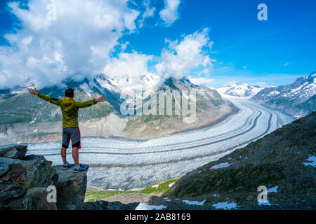 Man frohlockend mit ausgestreckten Armen am Aletschgletscher vom Eggishorn aus Sicht, Berner Alpen, im Kanton Wallis, Schweiz, Europa Stockfoto