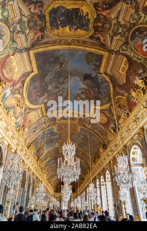 Große Porträt Low Angle View der Spiegelsaal im Schloss von Versailles. Die Masse der Besucher bewundern die Kronleuchter, vergoldete... Stockfoto
