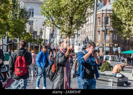 Amsterdam, Holland, September 2018 zu viele Touristen, die die Stadt Amsterdam Beweise dieser langen weiblichen Guide mit roten Regenschirm und lange leder j Stockfoto