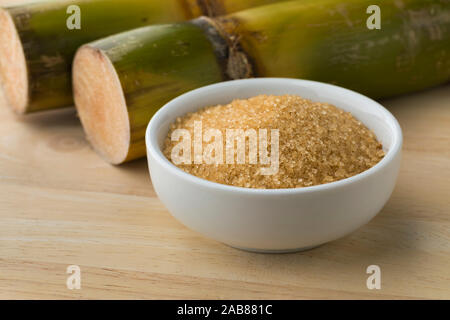 Schüssel mit Rohrzucker und frisches Zuckerrohr im Hintergrund Stockfoto