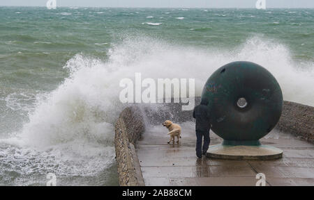 Brighton UK 26. November 2019 - ein Wanderer und sein Hund bekommt eine Tiefe von Wellen in Brighton Seafront als die Reste des tropischen Sturms Sebastien in Großbritannien ankommen, starke Winde und Regen die meisten Teile des Landes. Foto: Simon Dack/Alamy leben Nachrichten Stockfoto