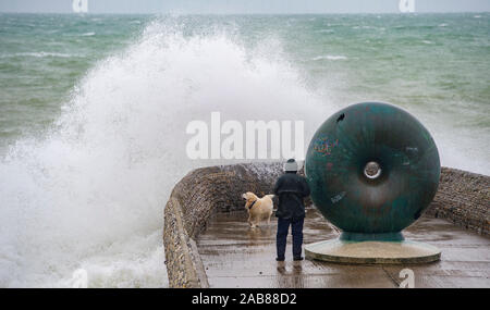 Brighton UK 26. November 2019 - ein Wanderer und sein Hund bekommt eine Tiefe von Wellen in Brighton Seafront als die Reste des tropischen Sturms Sebastien in Großbritannien ankommen, starke Winde und Regen die meisten Teile des Landes. Foto: Simon Dack/Alamy leben Nachrichten Stockfoto