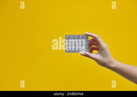 Frau hand mit schönen Maniküre holding Pillen in Blistergurt auf gelbem Hintergrund Stockfoto