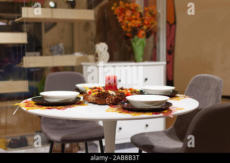 Schöne serviert Tabelle mit Blätter im Herbst Dekorationen und Kerze. Tisch für vier Personen für den Herbst Abendessen im Wohnzimmer. Stockfoto