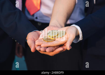 Junge asiatische Geschäftsmann und Goldene bitcoin vor seinem Internationalen multi-ethnische Teams in der modernen Stadt. Stockfoto