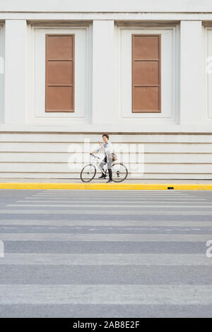 Überall von seinem Fahrrad. Seitenansicht der junge Unternehmer freuen uns auf dem Fahrrad Stockfoto