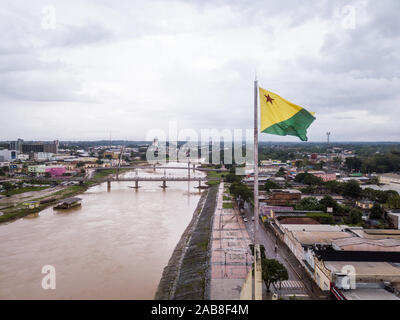 Luftaufnahme des Flusses Acre und der Flagge im amazonas. Rio Branco City Skyline, Center-Gebäude, Häuser, Straßen, Brücken an bewölkten Tag. Brasilien. Stockfoto