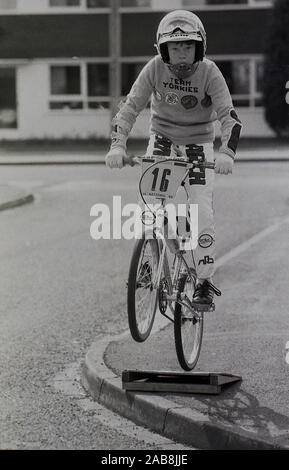 1987, Historic, ein junger BMX-Fahrer, der einen Sprung von einer selbstgebauten Rampe auf einem Bürgersteig in einer Straße in Yorkshire, England, Großbritannien, praktiziert. BMX ist eine Kurzform für Fahrrad-Motorcross, eine Freizeit- und Sportart, die in den 1980er Jahren auf BMX-Motorrädern mit Wettkampfrennen und Freestyle-BMX mit Sprüngen durchgeführt wurde, die der hier beobachtete Youngster praktiziert. Stockfoto