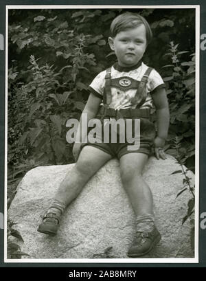 Europa, Deutschland, Hamburg, kleiner Junge in Lederhose sitzt auf einem Felsen und schaut in die Kamera, 1950er Jahre. /Europa, Deutschland, Hamburg, kleiner Junge aus Leder Hosen auf einem Felsen sitzt, sieht er der Fotografin, 1950. Stockfoto