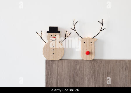 Eine lustige Holz Schneemann, mit einer roten Nase und einen Hut tragen, und ein Rentier Kopf gegen einen weißen Hintergrund Stockfoto