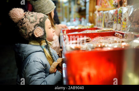 Nette junge Schwestern Spezialitäten Auswahl auf den traditionellen Weihnachtsmarkt in Riga, Lettland. Kinder kaufen Candy und Cookies auf Weihnachten. Happy Family Zeit an kühlen Stockfoto