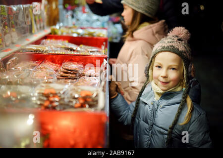 Nette junge Schwestern Spezialitäten Auswahl auf den traditionellen Weihnachtsmarkt in Riga, Lettland. Kinder kaufen Candy und Cookies auf Weihnachten. Happy Family Zeit an kühlen Stockfoto