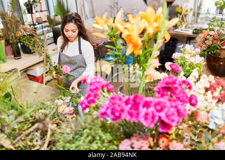 Asiatische Frau als Florist in der Ausbildung beim Binden Blumen im Store. Stockfoto