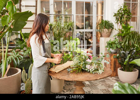 Asiatische Frau als Florist in der Ausbildung beim Binden Blumen Stockfoto