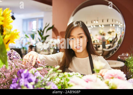 Junge asiatische Frau als Blumenhändler in Ausbildung in Flower Shop Stockfoto