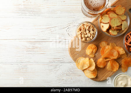 Chips, Bier, Bier, Snacks, Bier, Muttern, Saucen auf weißem Hintergrund Holz, Platz für Text. Ansicht von oben Stockfoto