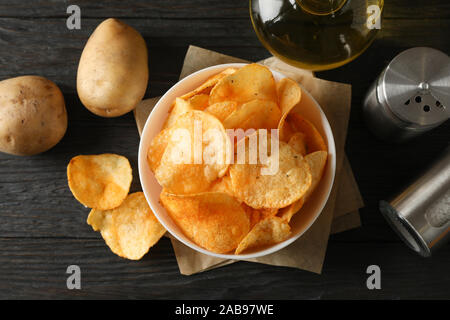 Kartoffelchips in eine Schüssel für das Handwerk. Kartoffel-, Gewürz, Oliven Öl auf Holz- Hintergrund, Nahaufnahme. Ansicht von oben Stockfoto