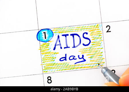 Frau Finger mit Pen schreiben Erinnerung-AIDS-Tag im Kalender. Dezember 01. Stockfoto