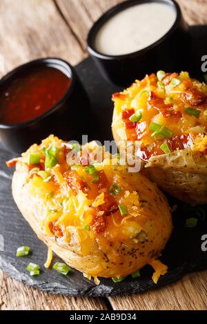 Gebackene Kartoffeln gefüllt mit Cheddar Käse und Speck Nahaufnahme auf dem Tisch. Vertikale Stockfoto