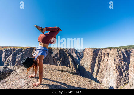 Schöne Frau macht Handstand an der schwarzen Schlucht des Gunnison Stockfoto