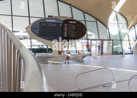 JFK Airport Queens NY-September 03 2019: Air Hostess an der Rezeption in der TWA Hotel mit einem analogen flapping Display hinter ihr. Queens NY Sep Stockfoto