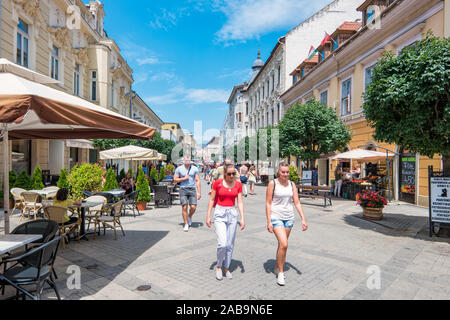 Fußgänger zu Fuß in der Innenstadt von Győr Ungarn an einem sonnigen Tag. Stockfoto