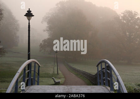 Holzbrücke und alten Straßenlaterne im Stil des 19. Jahrhunderts im Nebel im Herbst. Lage: Park Sonsbeek, Arnhem, Niederlande. Stockfoto