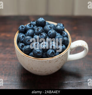 Frische Heidelbeeren in einer Schale auf einem dunklen Hintergrund. Seitenansicht, Makro. Blaue reife Beeren schließen bis auf braunem Holz- Hintergrund. Stockfoto