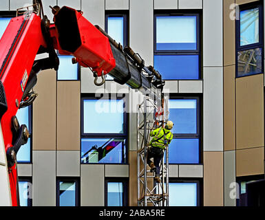 Cherry Picker und Arbeiter ersetzen Wohnung Fliesen Stockfoto