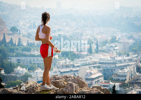 In roten Hosen auf einem Hügel mit Blick auf Athen ständigen Jugendlich Stockfoto