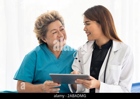Asiatische vertrauen Arzt mit digitalen tablet Ausdruck Gesundheit Interessen mit alten ältere Frau Patienten sitzen auf Rollstuhl Stockfoto