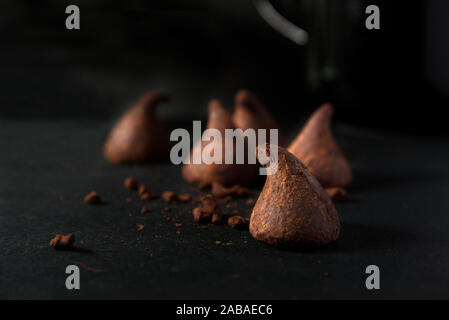 Schokolade Trüffel mit Pulver auf einem schwarzen Holztisch einer rustikalen Küche. Leere Raum für Editor's Text. Stockfoto