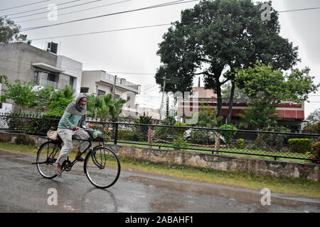 Ein Mann fährt mit dem Fahrrad entlang einer Straße bei starken Niederschlägen in Rajpura Stadt von Patiala Bezirk. Stockfoto