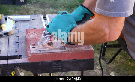 Tile cutter Industrie anlagen. Arbeiter schneiden Bodenplatten für die Verlegung auf der Terrasse mit Kreissäge elektrische Stockfoto